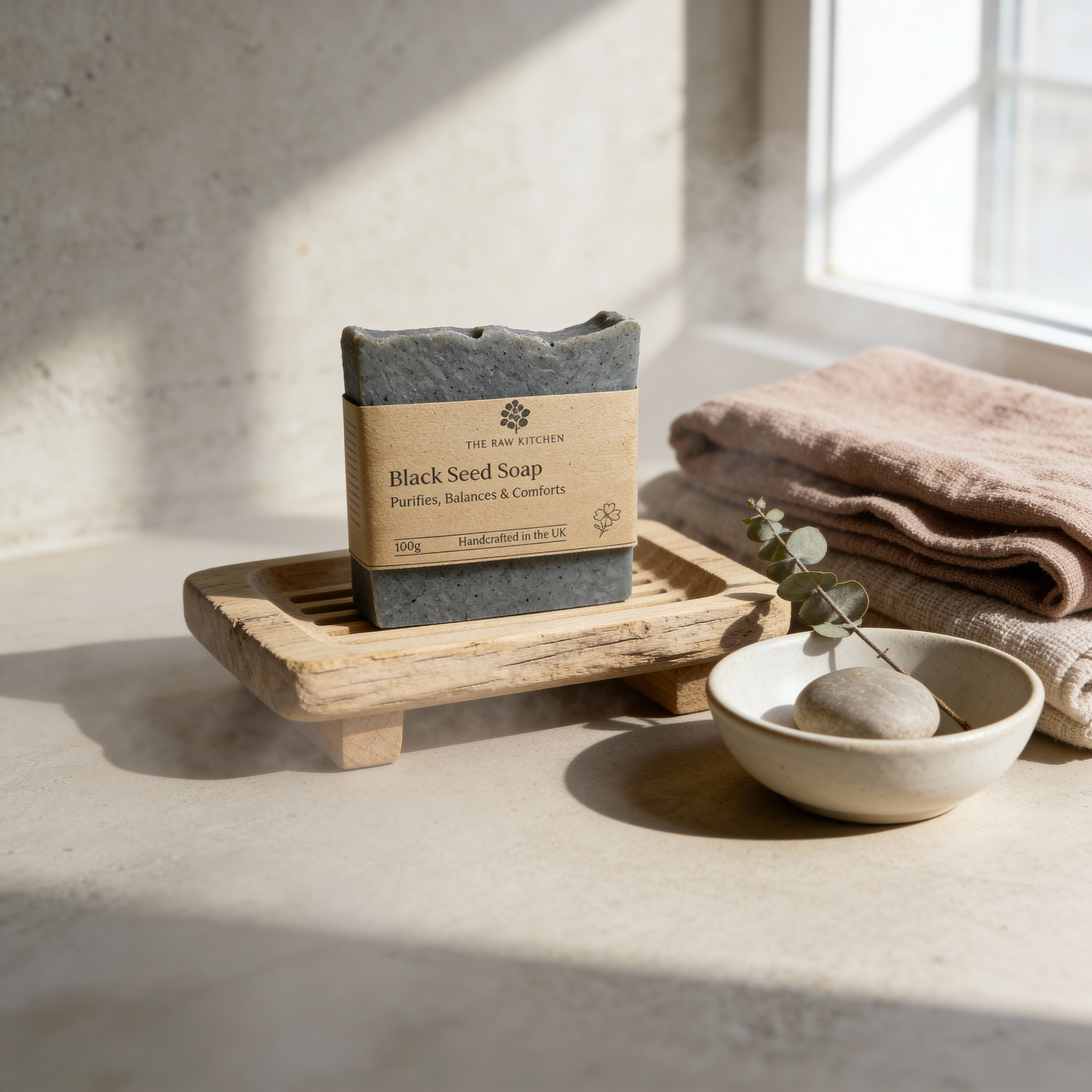 Black seed soap on a wooden tray with a bowl and towel in a bright room
