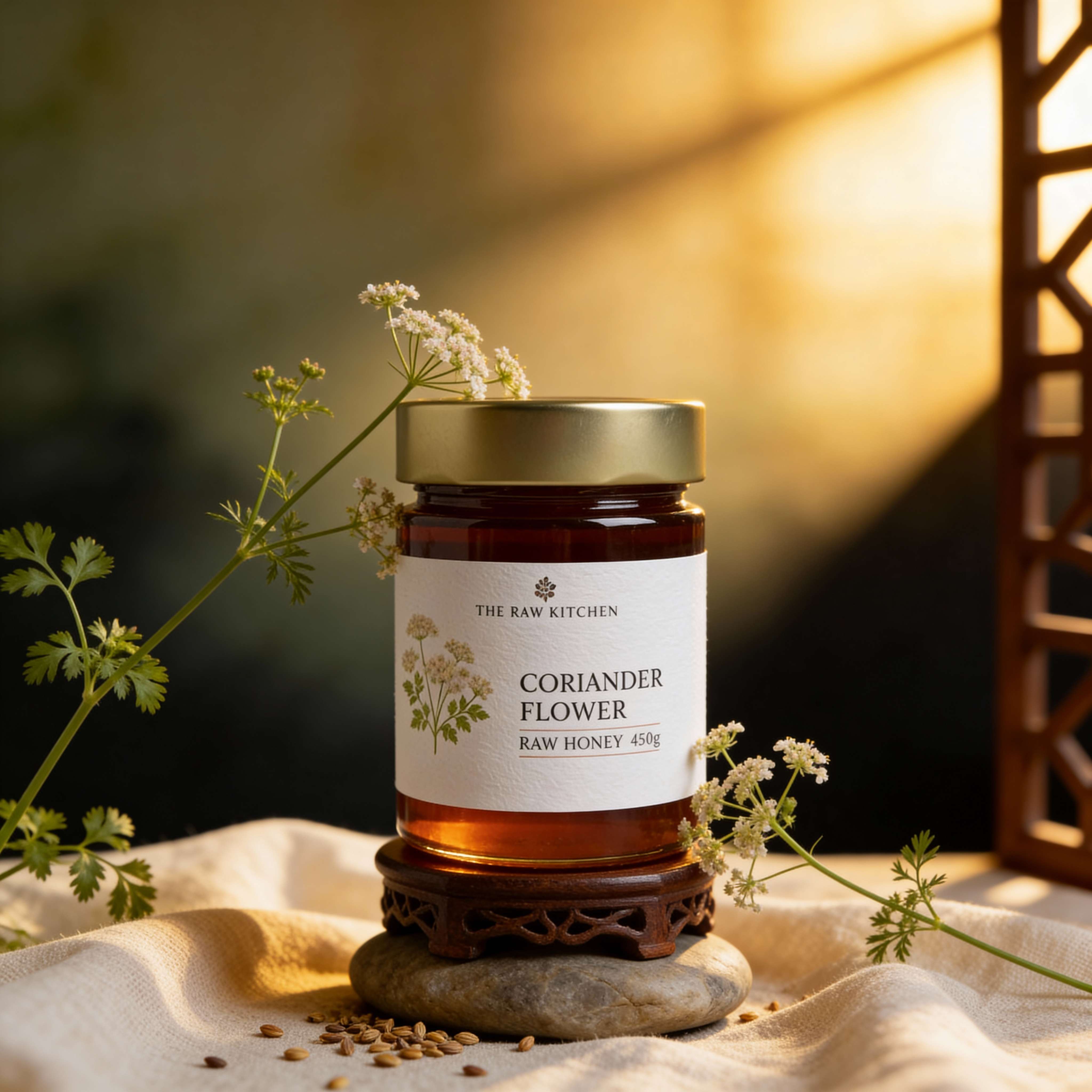 Jar of coriander flower raw honey on a stone with herbs and flowers around, warm lighting.