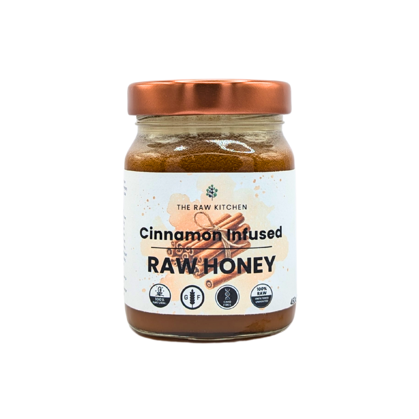 A 450g glass jar of Cinnamon Infused Raw Honey with a rose gold lid and branded label - The Raw Kitchen UK.