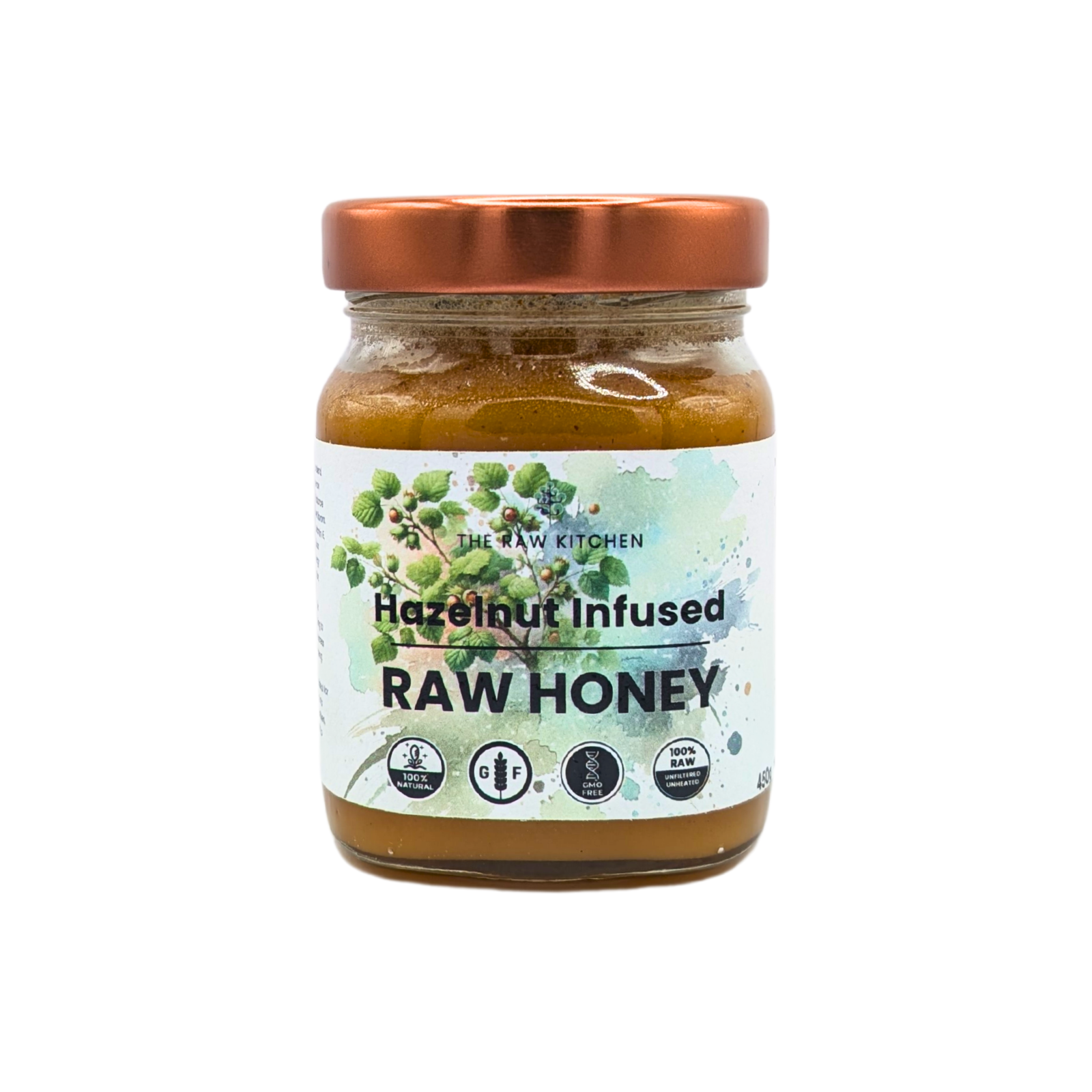A 450g glass jar of Hazelnut Infused Raw Honey with a rose gold lid and branded label - The Raw Kitchen UK.