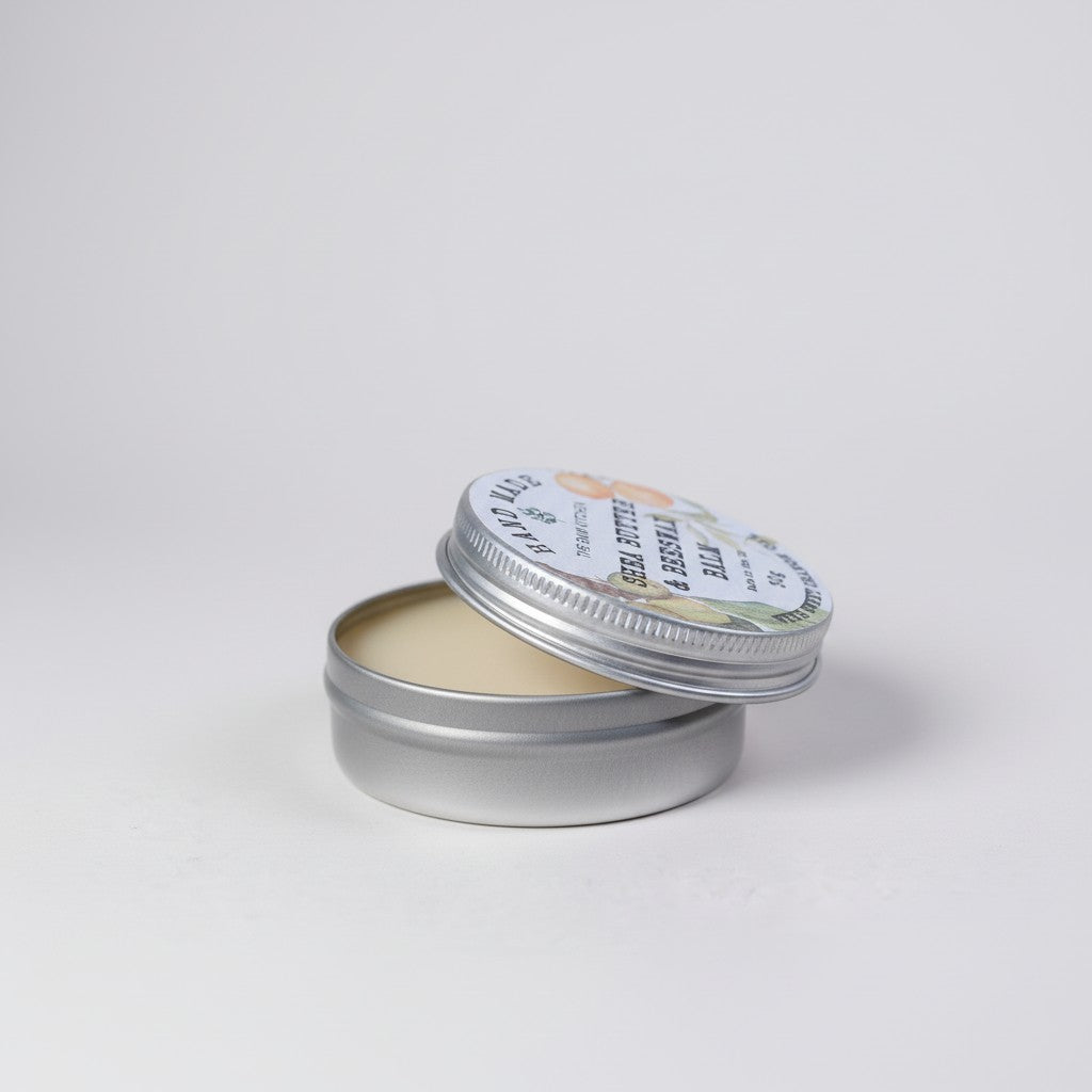 Metal tin with a lid containing a white cream on a light gray background