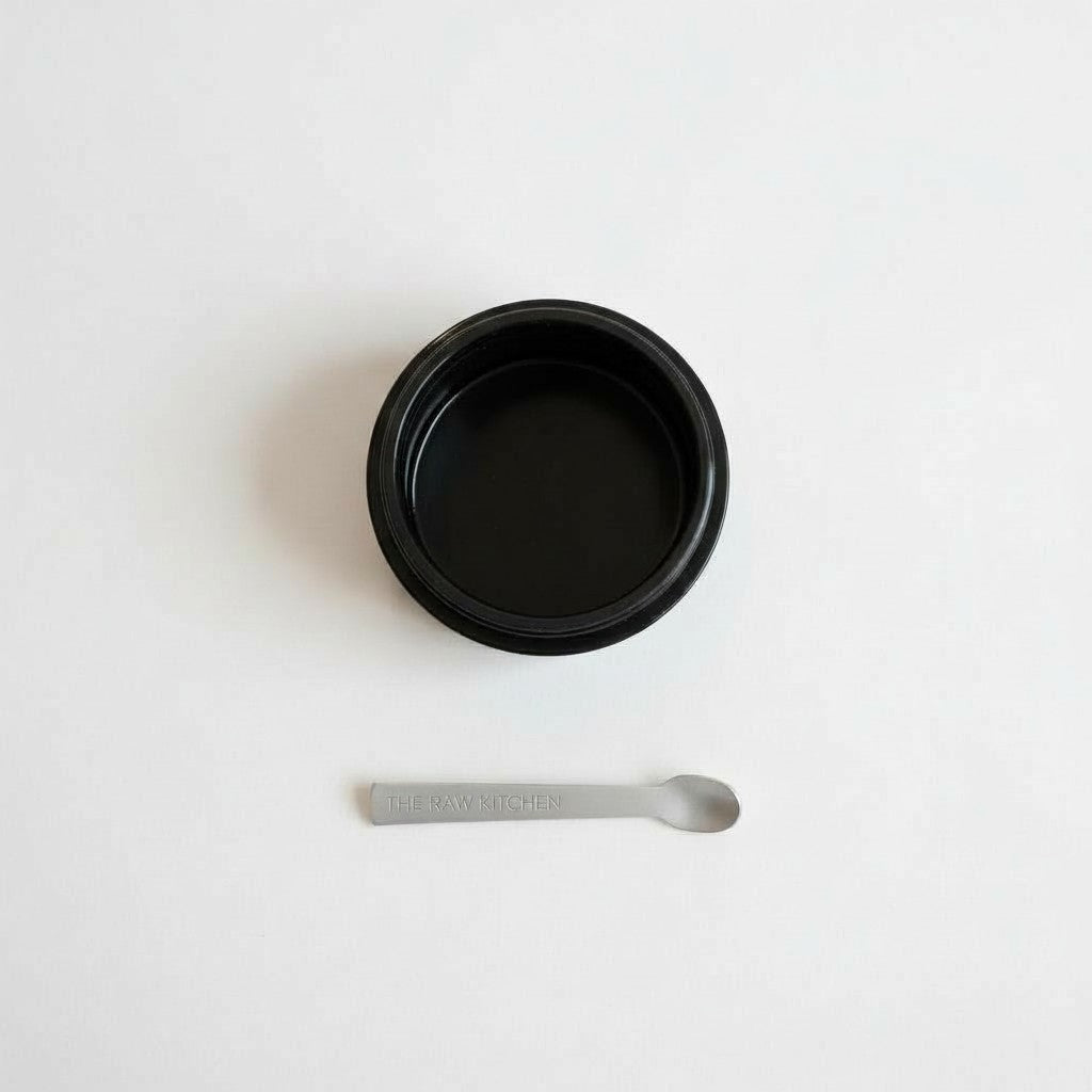 Black container with a small spoon on a white background