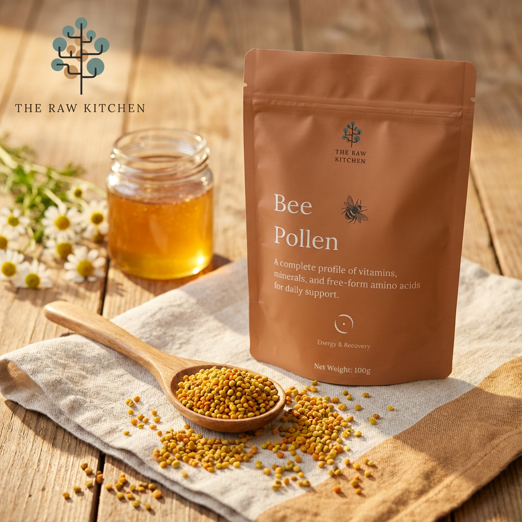 Bee pollen package with a spoonful of pollen and honey on a wooden surface, branded 'The Raw Kitchen'.
