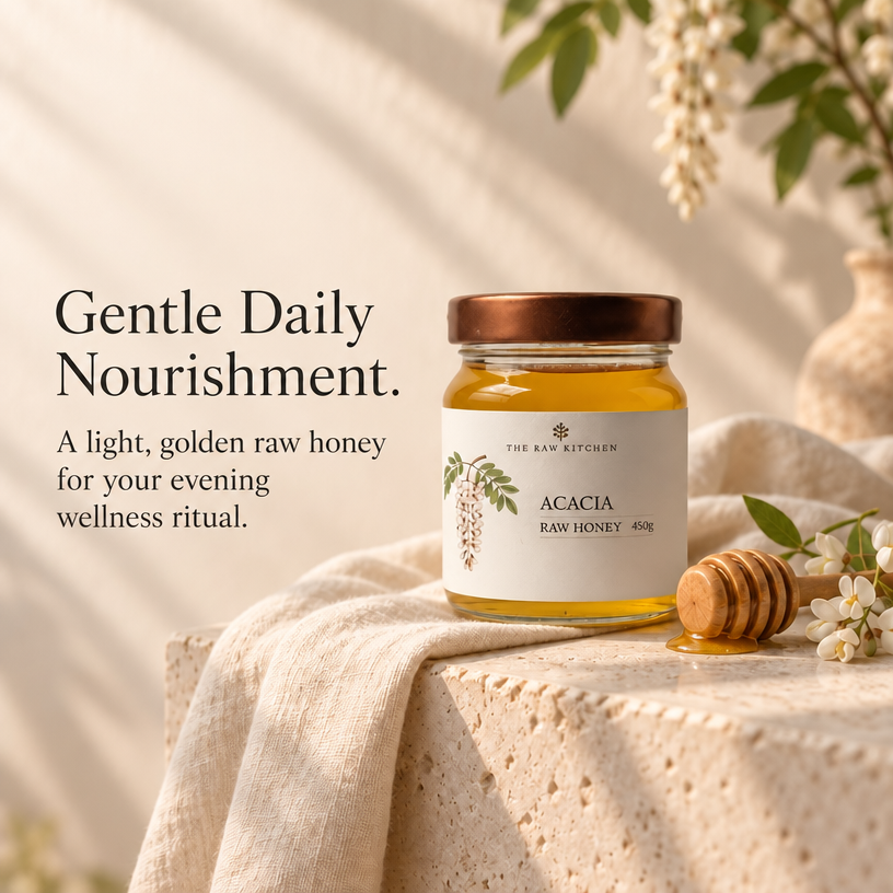 A glass jar of raw honey with a copper lid and white label sits on a draped beige cloth beside a honey dipper and small white flowers. Text on the left reads, 'Gentle Daily Nourishment.