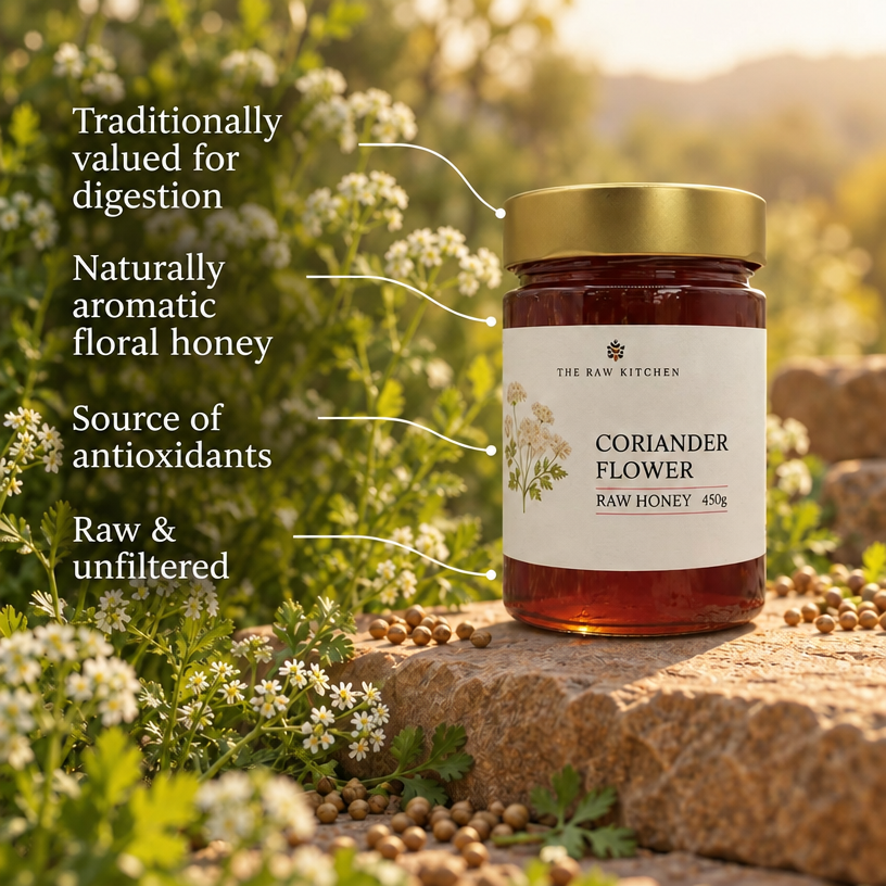 Coriander flower raw honey jar with gold lid beside scattered coriander seeds and flowers.