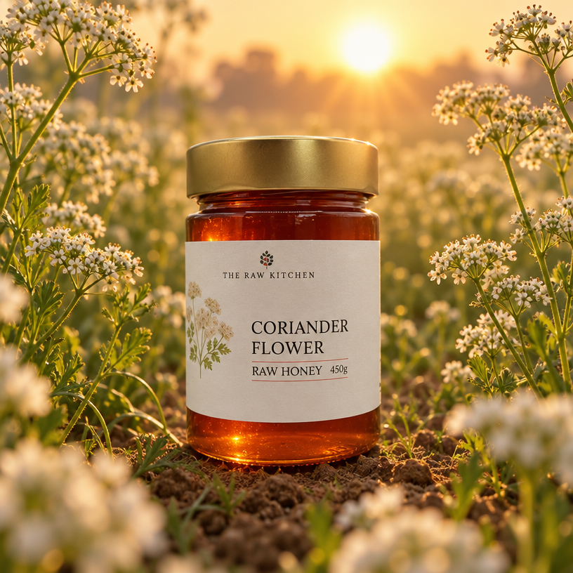 Coriander flower raw honey jar with gold lid surrounded by small white blossoms.
